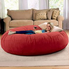 a woman laying on top of a large red bean bag chair in a living room