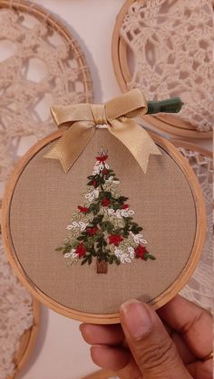 someone is holding up a small cross stitch christmas tree