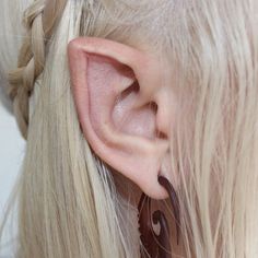 a close up of a person with long blonde hair wearing earrings and earrings