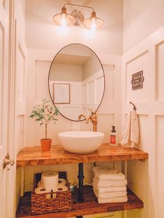 a bathroom with a sink, mirror and towels on the shelf in front of it