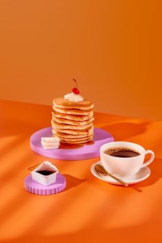 a stack of pancakes sitting on top of a plate next to a cup of coffee