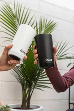 two people holding coffee mugs in their hands, one is black and the other is white