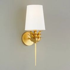 a gold wall light with a white shade on the side and a flower in the middle