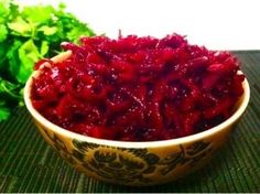 a bowl filled with cranberry sauce sitting on top of a table next to lettuce