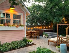 an outdoor patio with wooden furniture and potted plants on the side of the house