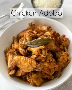 chicken adobo in a white bowl with a spoon and rice on the side