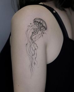 a black and white photo of a woman's shoulder with a jellyfish tattoo on it