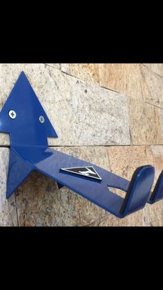 a blue sculpture on the side of a building with an arrow shaped object attached to it