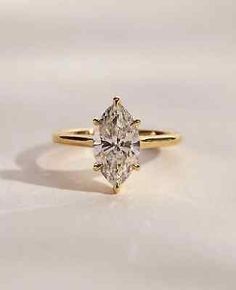 a yellow gold engagement ring with an oval cut diamond in the center, on a white surface