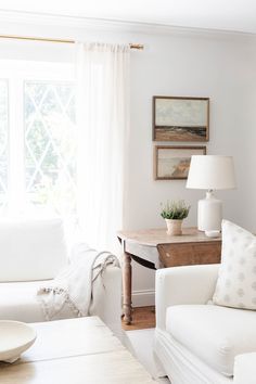 a living room with white furniture and curtains