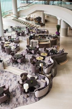 an empty lobby with many couches and tables on the floor in front of a staircase