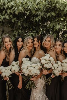 a group of women standing next to each other holding bouquets of white flowers in their hands