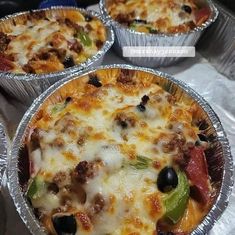 three pizza pies sitting on top of tin foil pans covered in cheese and toppings