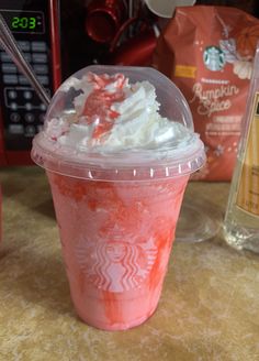 a pink drink with whipped cream and candy canes in it sitting on a table