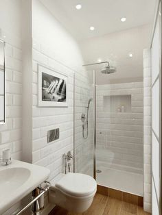 a bathroom with white tile walls and wooden flooring, along with a walk in shower