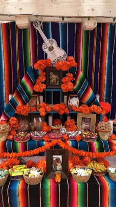 a mexican themed dessert table with orange flowers on it and an acoustic guitar hanging from the ceiling