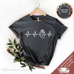 Get your heart racing with our Heart Heartbeat Shirt! Perfect for cardiac nurses, EKG techs, paramedics, and doctors, this shirt is a must-have for anyone in the medical field. With its unique design featuring a heart rhythm, this shirt will show off your expertise and passion for what you do. Made from high-quality materials, it's comfortable to wear all day long and looks great with any outfit. Whether you're at work or out on the town, this shirt is sure to turn heads and start conversations. Ekg Tech, Emt Shirts, Cardiac Nurse, Heart Rhythm, Cardiac Nursing, Tech Shirt, Design Text, Medical Field, Cardiology