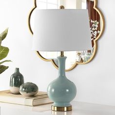 a blue vase sitting on top of a white table next to a mirror and lamp