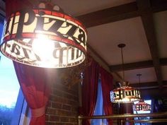 a lamp hanging from the ceiling next to a window in a room with red curtains