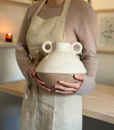 a woman in an apron holding a white vase