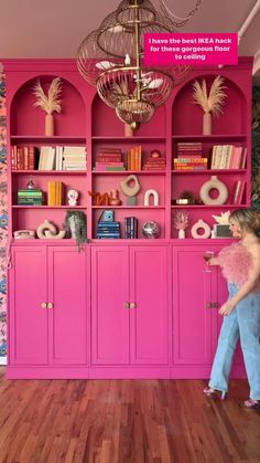 a girl is standing in front of a pink bookcase