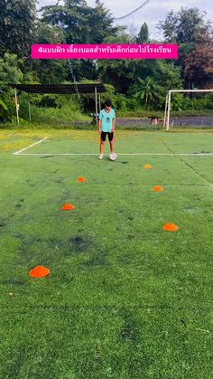 a man standing on top of a lush green field next to orange frisbees