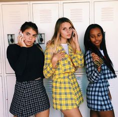 three beautiful young women standing next to each other in front of lockers talking on cell phones