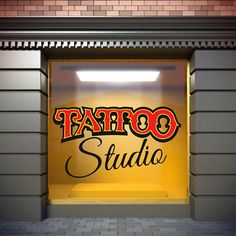 a tattoo studio sign on the side of a store front window with an open door