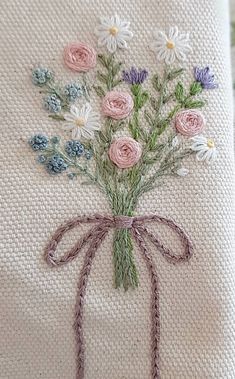 a bouquet of flowers sitting on top of a white pillow with a ribbon around it