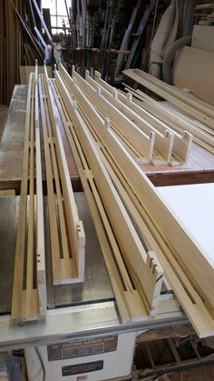 several pieces of wood sitting on top of a machine in a room filled with wooden planks