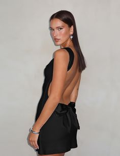 a woman in a short black dress posing for the camera with her back to the camera