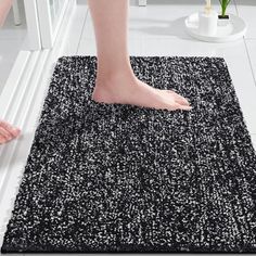 a person standing on top of a black and white rug next to a bathroom sink