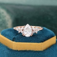 an engagement ring with three diamonds on it sitting on top of a blue velvet cushion