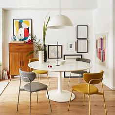 a dining room table with chairs and pictures on the wall in front of it,