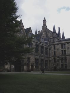 a person walking in front of a large building with many windows and towers on it