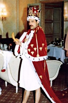 a man in a red and white costume holding a piece of bread while standing next to a table