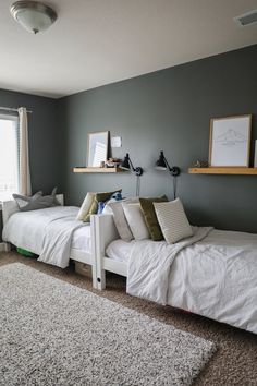 two twin beds in a bedroom with gray walls and white rugs on the floor