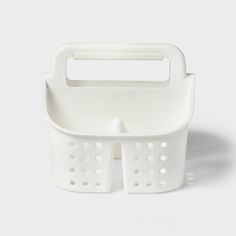 a white plastic basket with handles and holes on the bottom, sitting against a white background