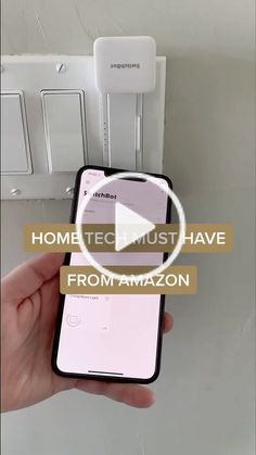 someone is holding an iphone in front of a light switch box with the text, home tech must have from amazon