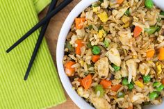 a bowl filled with rice and vegetables next to chopsticks