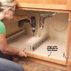 a woman is drilling holes in the cabinet