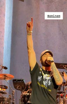 a man with his hand up in the air while singing into a microphone on stage