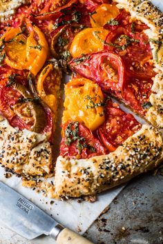 a pizza with tomatoes and herbs on it is cut in half to show the crust