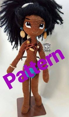 a crocheted doll with black hair and earrings on top of a wooden stand