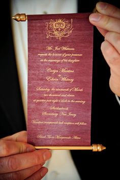 a person holding up a red and gold wedding card