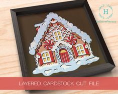 a paper cut out of a gingerbread house on a wooden table with text overlay that reads layered card stock cut file