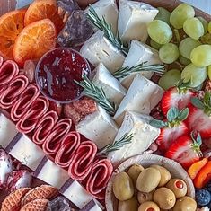 an assortment of cheeses, fruits and crackers on a platter with fruit