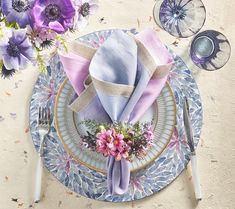 a blue and white plate topped with purple napkins next to a bouquet of flowers