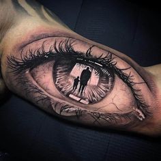 a man's arm with an eye tattoo on it and the image of a person holding