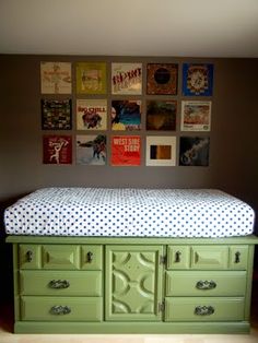 an image of a green dresser with pictures on the wall above it and below it